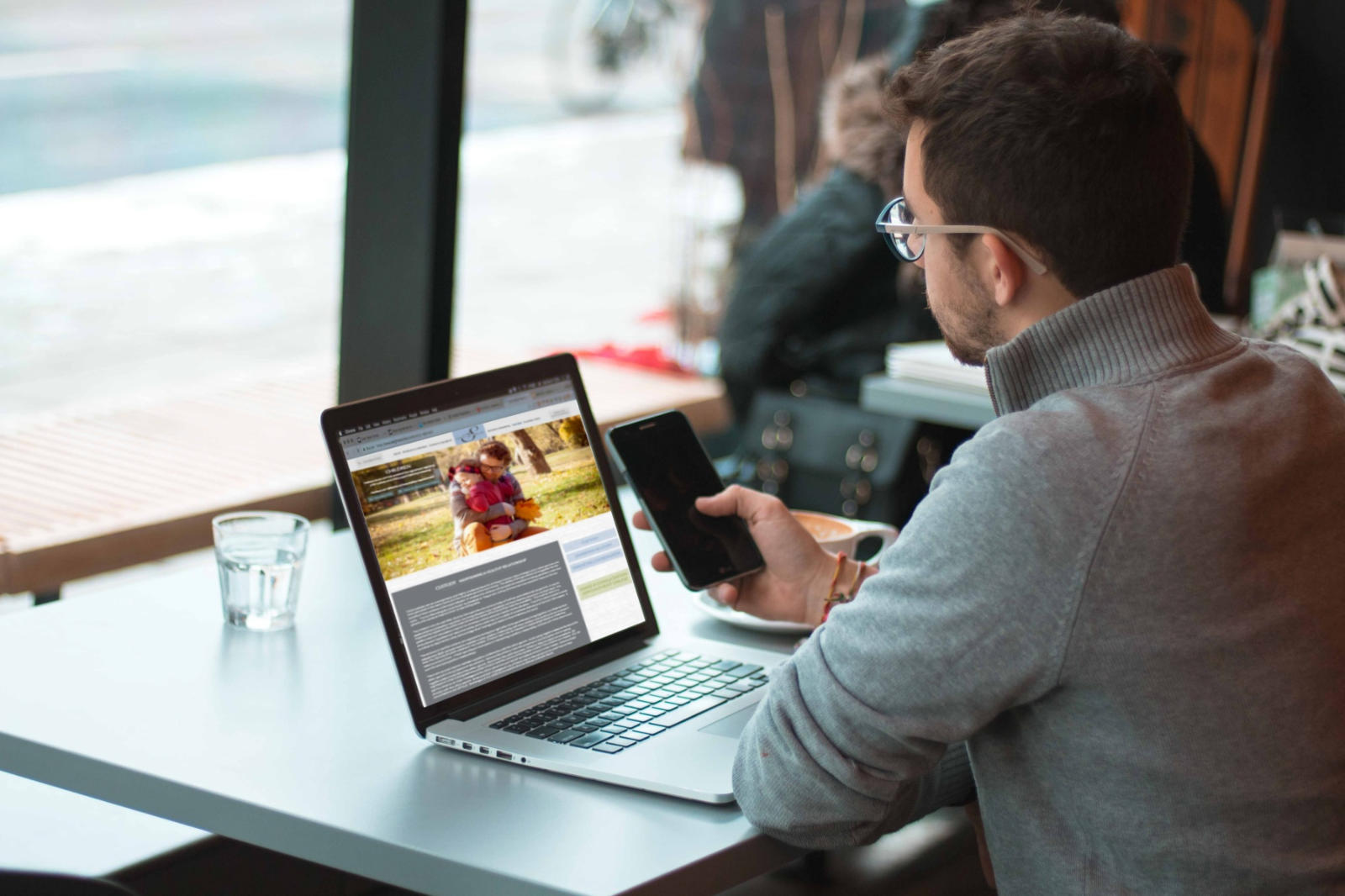 Image of man looking at the Sams Legal web site on his laptop and holding his phone