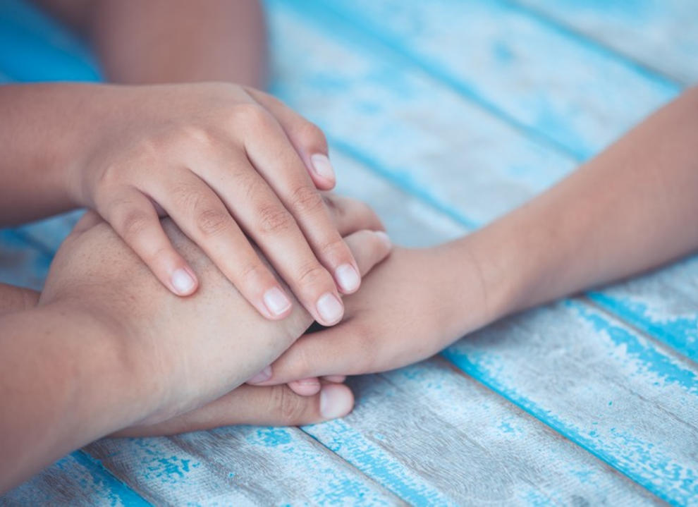 Image of adult and children stacking their hands on top of each other in a promise gesture