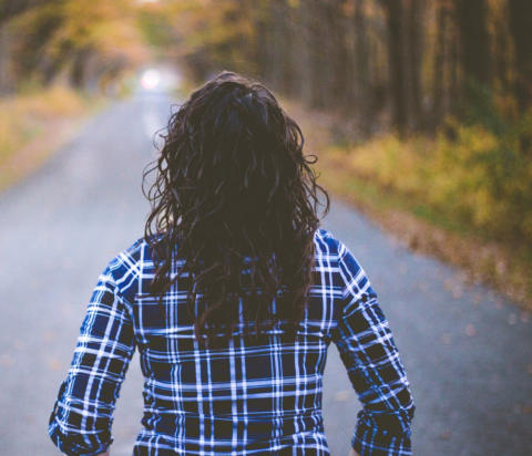 Image of a woman looking down the road to an inviting light ahead