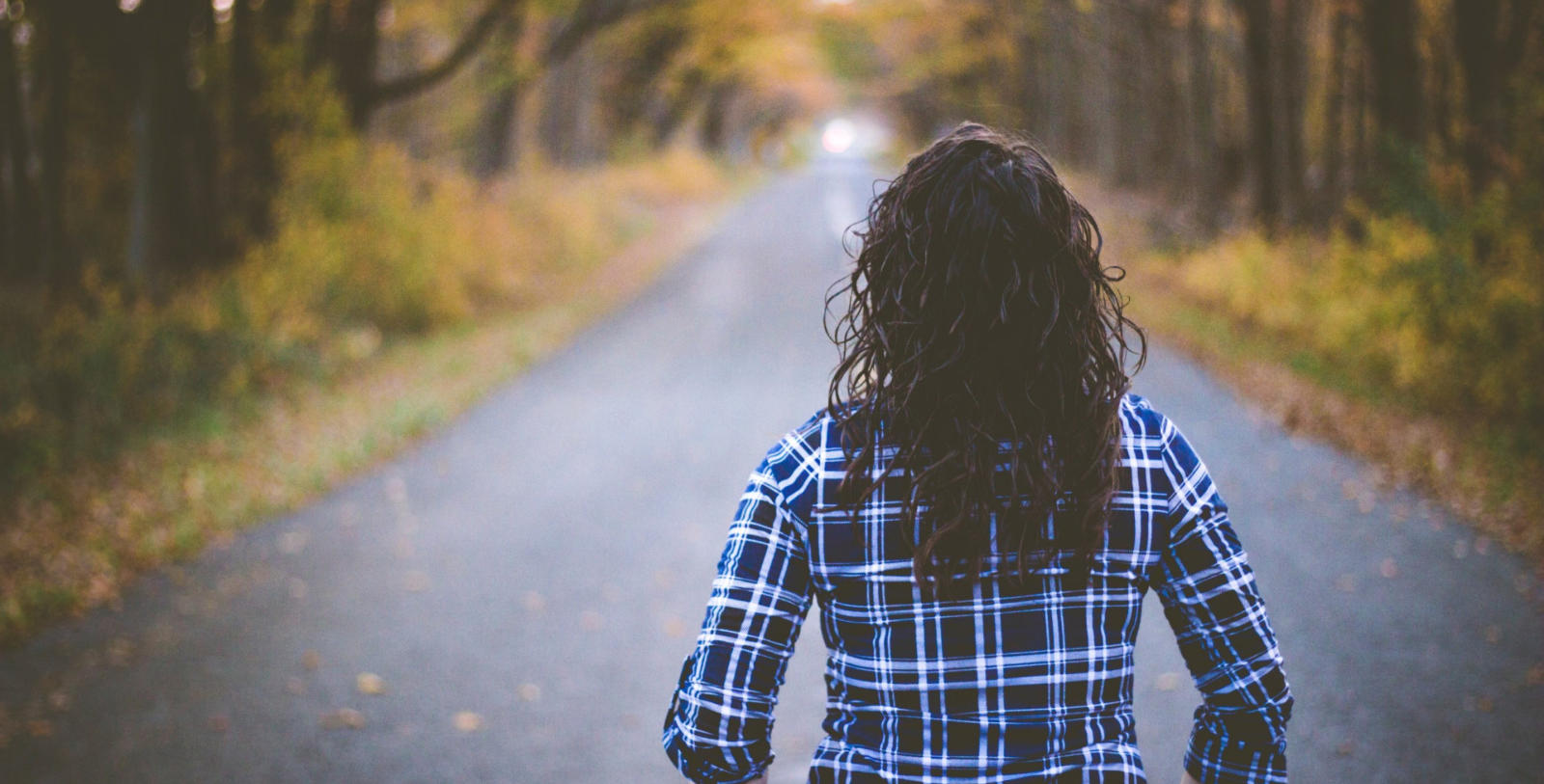 Image of a woman looking down the road to an inviting light ahead