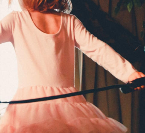 Image of young girl in pink dress skipping through her apartment