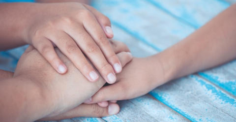 Image of adult and children stacking their hands on top of each other in a promise gesture