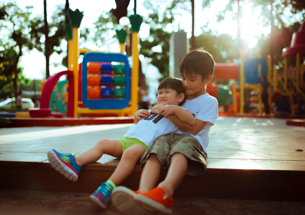 Image of a big brother hugging his little brother on a playground