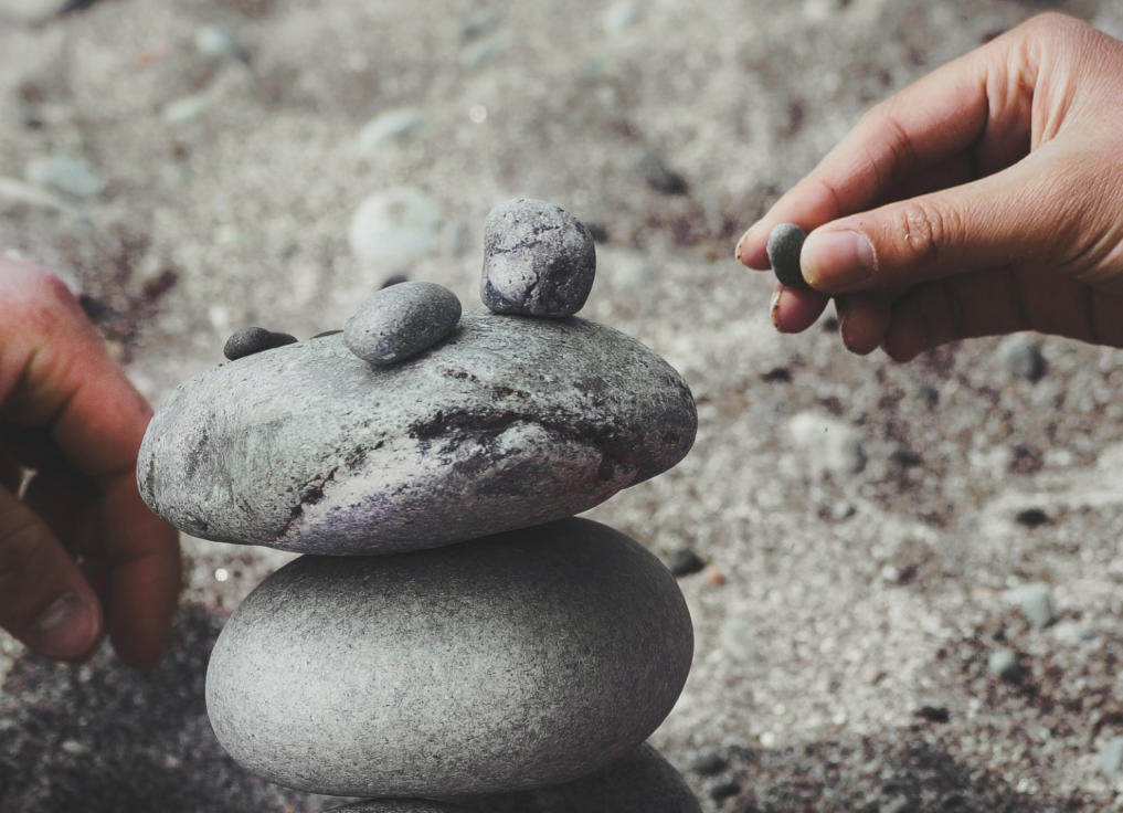 Image of two people balancing pebbles in a stack